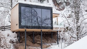 Een moderne cabin met een groot raam, houten gevel en een stenen fundering.
