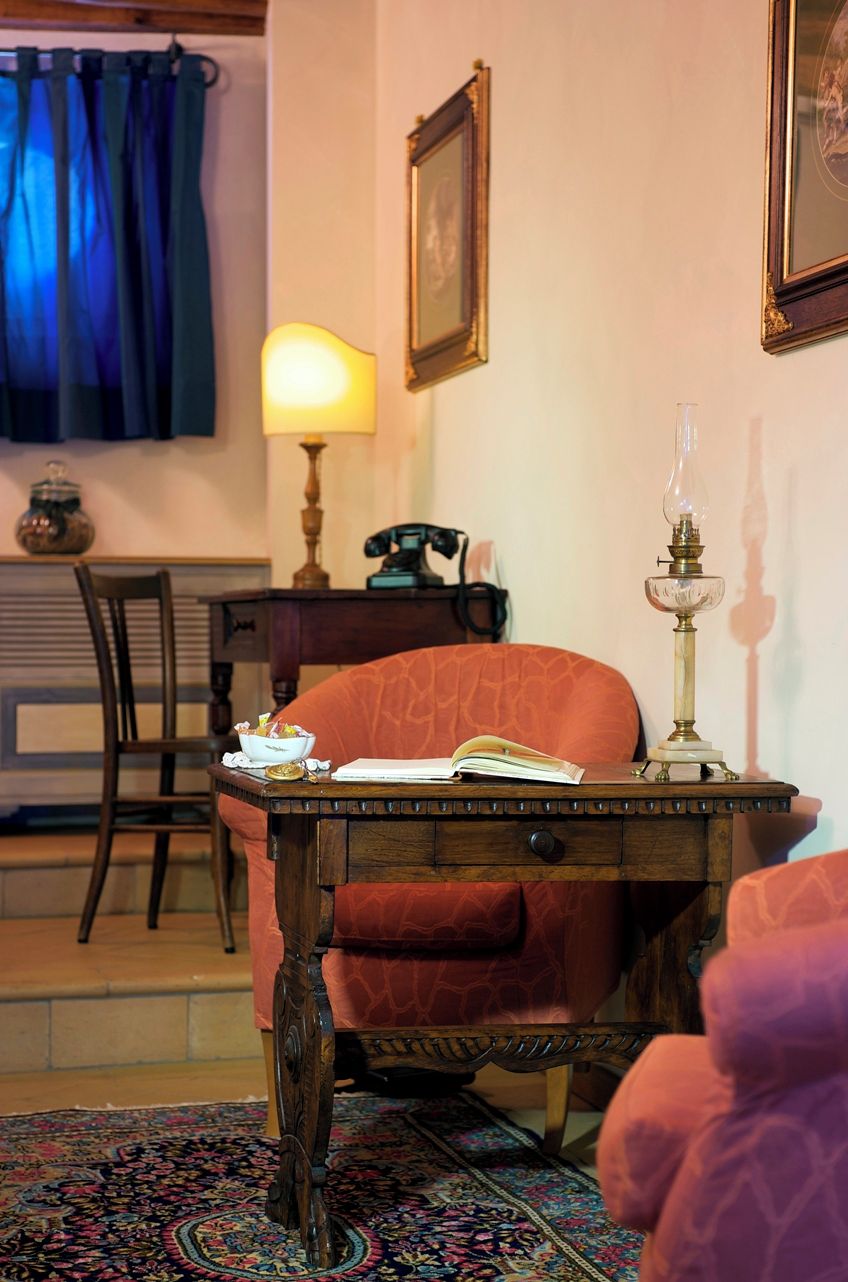 A cozy room with a wooden desk, a chair, a lamp, and a framed picture on the wall.