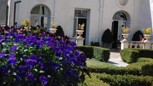 A building with arched windows and a well-maintained garden with purple flowers and trimmed hedges. - Palazzo Leti Residenza d'Epoca (Spoleto)