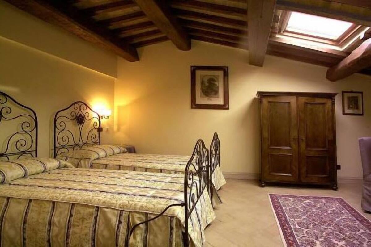 A bedroom with two beds, a wooden wardrobe, and a skylight.