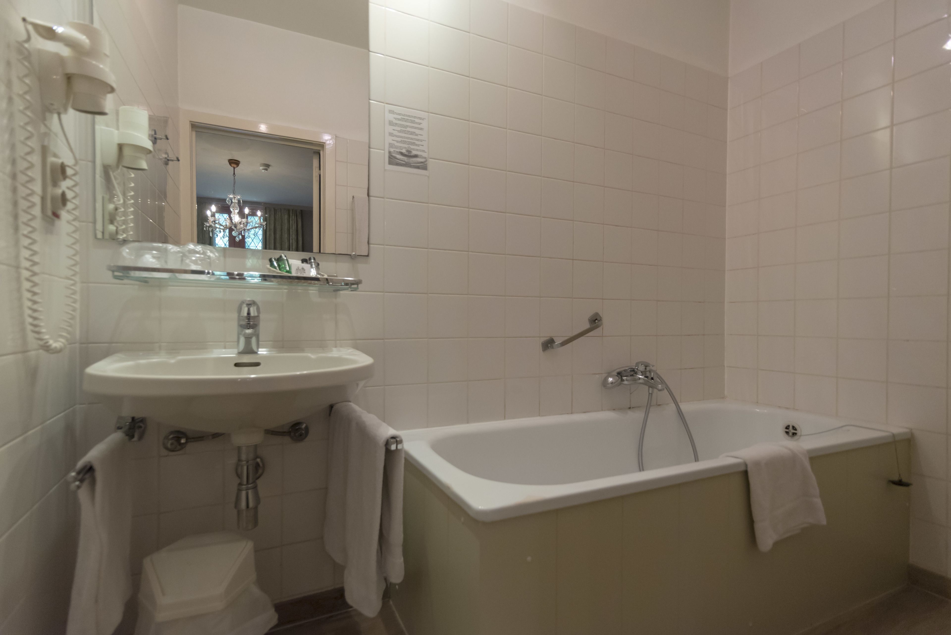Een badkamer met een wastafel, spiegel en bad.