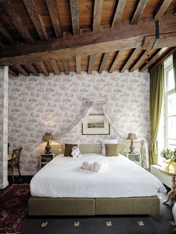 A bedroom with a large bed, floral wallpaper, a canopy, and a view of the outside through a window. - Canal View Hotel Ter Brughe by CW Hotel Collection (Bruges)