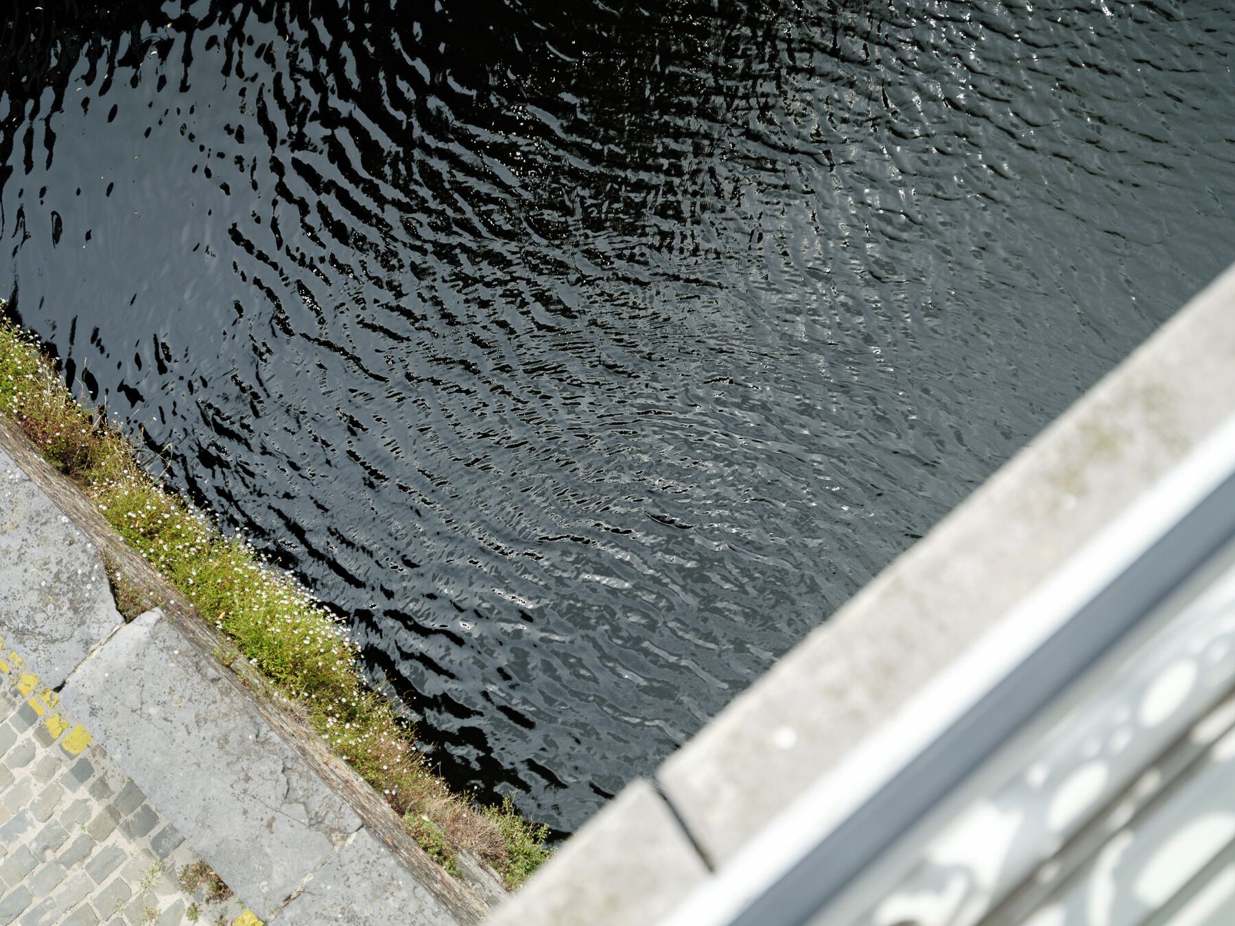 A calm water body adjacent to a stone pathway.