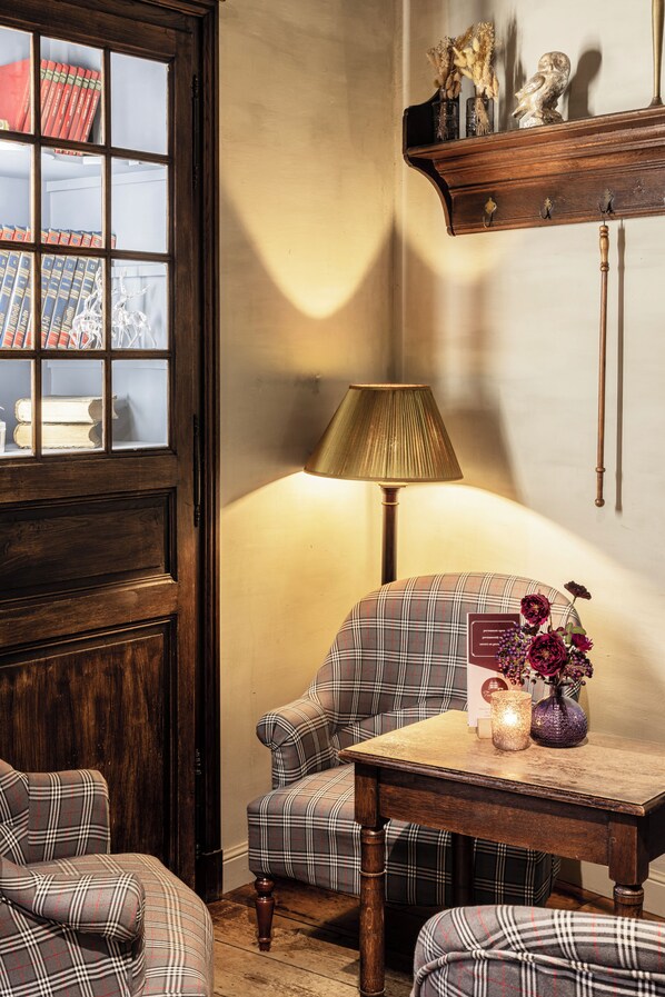 Una habitación acogedora con mobiliario escocés, una puerta de madera y una mesa con una lámpara y flores.