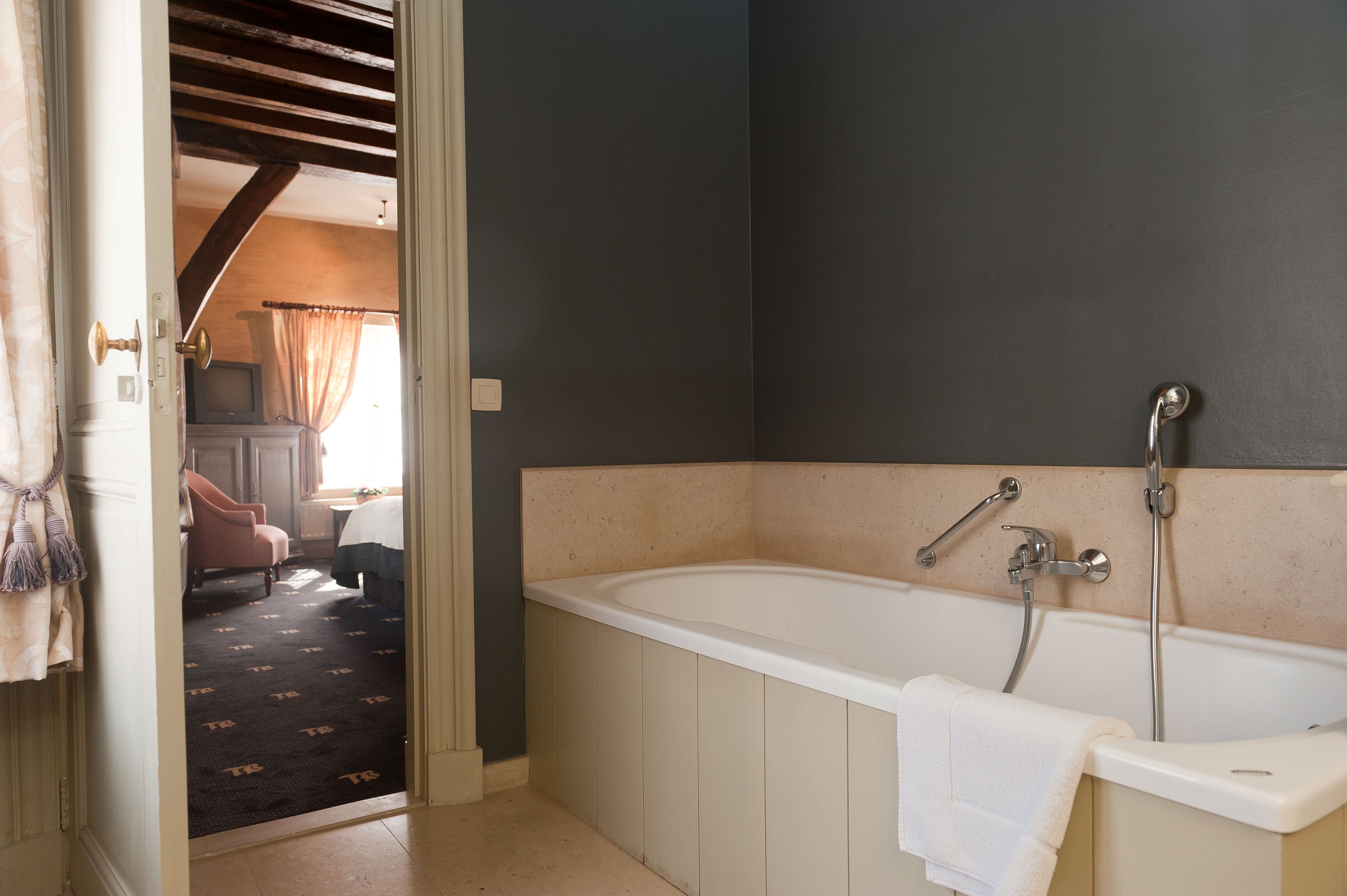 A bathroom with a bathtub, a shower, and a towel hanging on the side.