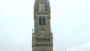 A historic building with a tall clock tower, featuring a central entrance and multiple flags.