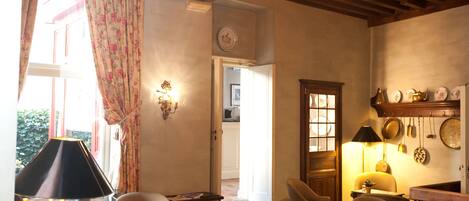 A cozy living room with wooden beams, a fireplace, and a dining area with a table and chairs.