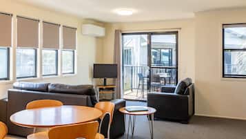 Una sala de estar moderna con sofá, sillas, una mesa y un televisor.