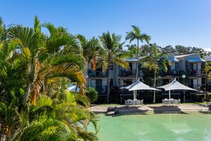 Un resort con piscina, mobiliario exterior y palmeras.