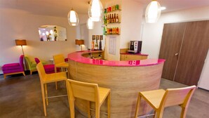 A reception area with a curved wooden counter, several wooden chairs, a mirror, a shelf with bottles, and a door in the background. - Hotel Anne de Bretagne (Rennes)