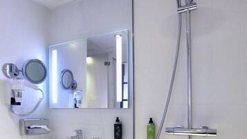 A modern bathroom with a white sink, two mirrors, a handheld showerhead, and a handheld shower bar.
