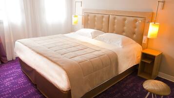 A hotel room with a large bed, two bedside lamps, and a purple carpet with text.