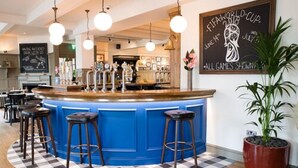 A bar area with a blue counter, bar stools, and a checkered floor. There is a chalkboard with FIFA World Cup 2018 text. - The Fox & Goose Hotel (London)