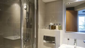 A modern bathroom with a glass-enclosed shower, a white sink, and a mirror above it.