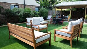 A patio with wooden furniture and a covered seating area. - The Fox & Goose Hotel (London)