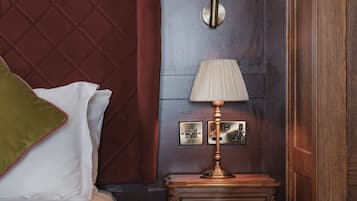 Una habitación de hotel con una cama, una mesita de noche con lámpara y un muro con paneles decorativos.