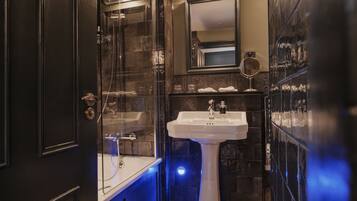 Un baño con cabina de ducha de vidrio, lavamanos pedestal y espejo sobre él.