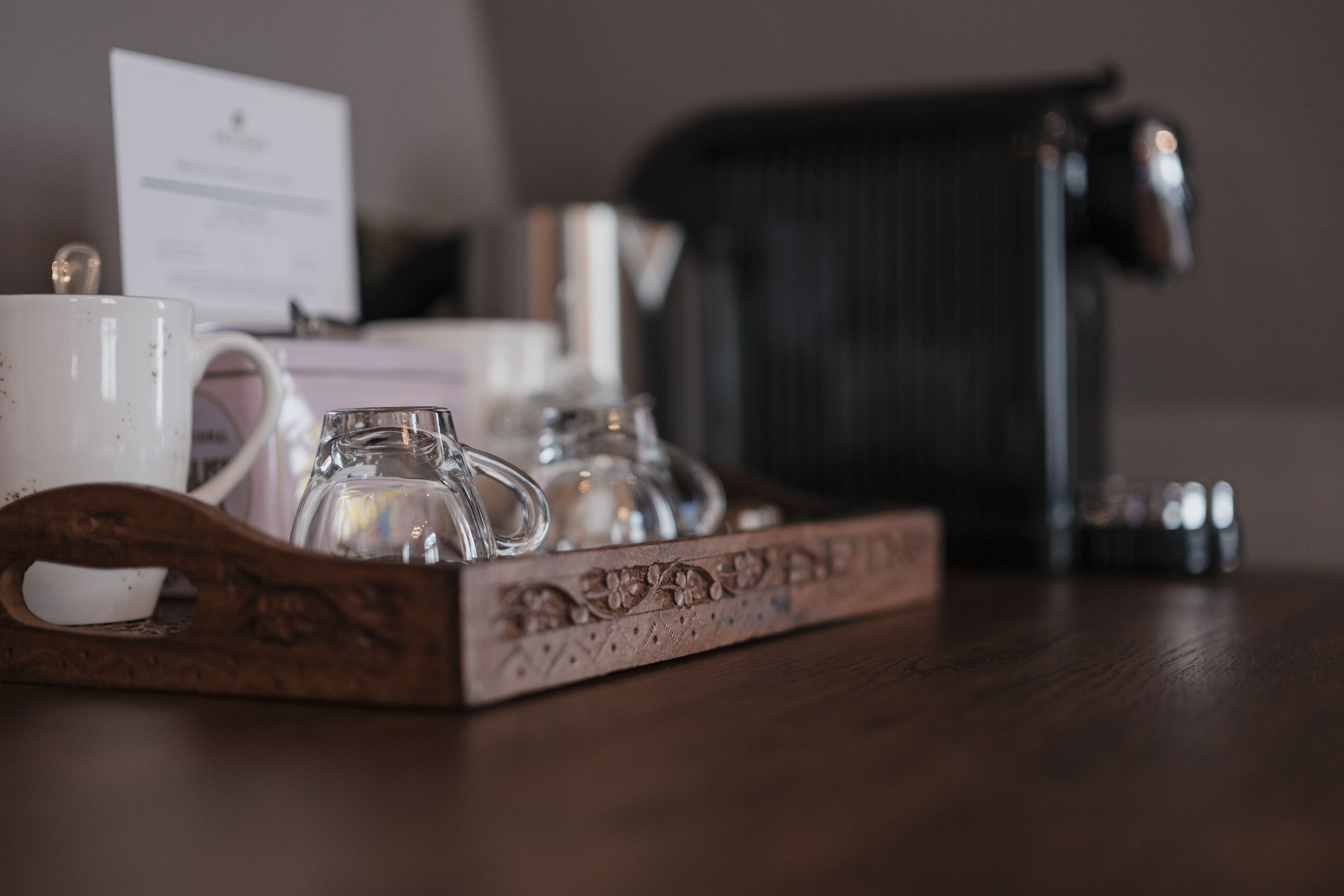 A tray with a white mug, a glass, and a small pitcher on a wooden table.
