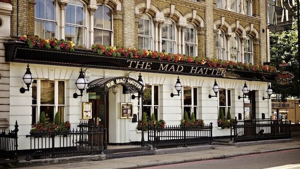 A traditional building with a sign reading "The Mad Hatter." It features classic architecture with arched windows and a black iron fence. - The Mad Hatter Hotel (London)