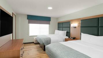 Une chambre d’hôtel avec deux lits, une télévision, une table de chevet, une commode et une fenêtre donnant sur un beau paysage.