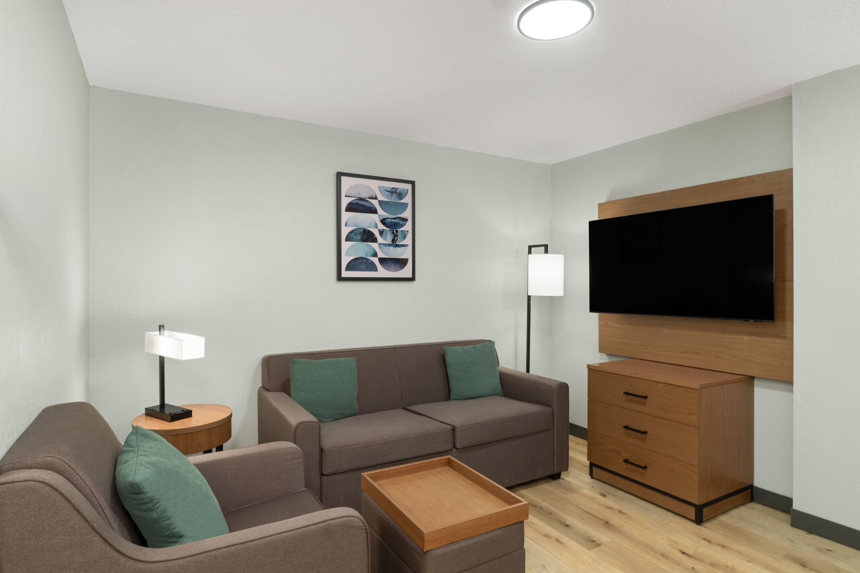 Una sala de estar moderna con un sofá, una mesa de centro, un televisor y una mesita auxiliar.