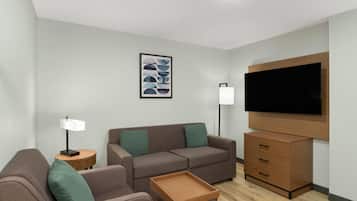 Una sala de estar moderna con un sofá, una mesa de centro, un televisor y una mesita auxiliar.