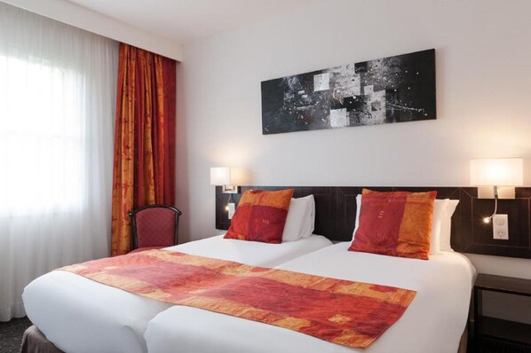A hotel room with a large bed, two bedside lamps, a headboard, and a cityscape painting on the wall. - La Bertelière, The Originals Relais Rouen (Saint-Martin-du-Vivier)