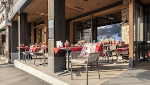 Un espacio al aire libre para comer con mesas y sillas, un muro de piedra y vistas a montañas.