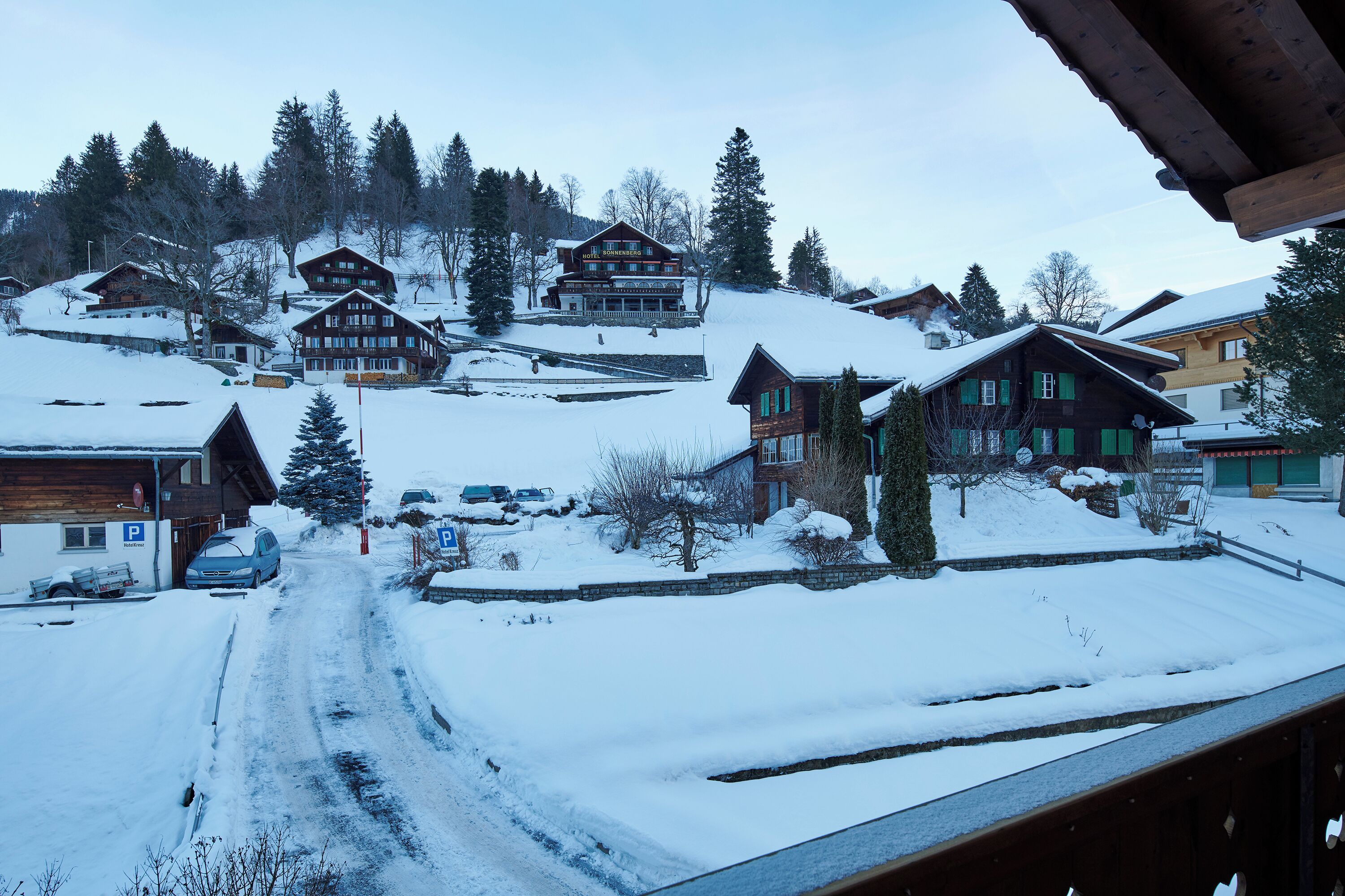 Un pueblo cubierto de nieve con casas de madera, un telesilla y un cielo despejado.