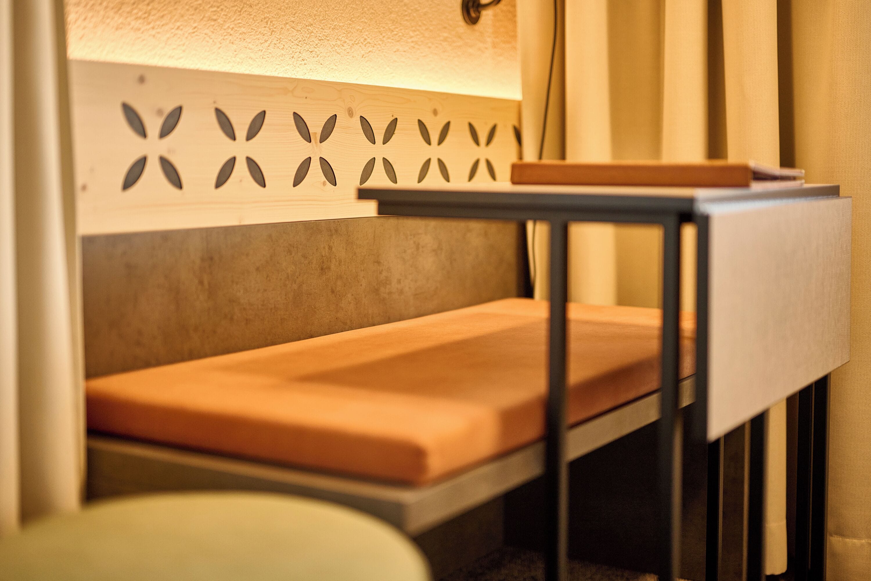 A compact bed with a wooden headboard and a bedside table with a lamp.