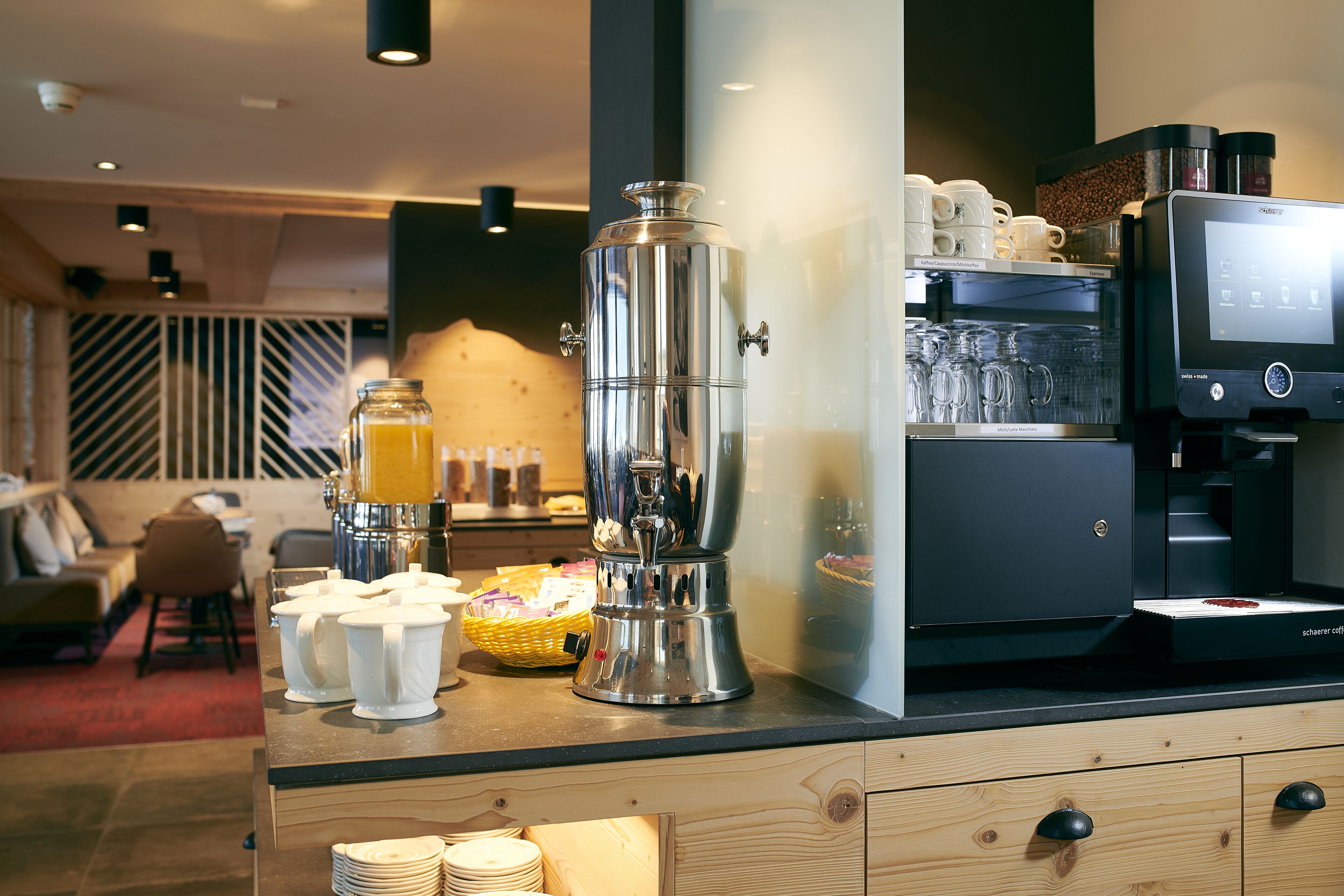 A modern coffee station with a coffee machine, milk frother, and a coffee urn.
