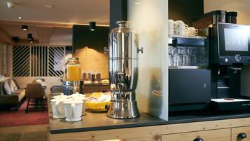 A modern coffee station with a coffee machine, milk frother, and a coffee urn.