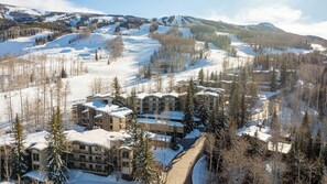 A snow-covered ski resort with multiple buildings, ski lifts, and a mountainous backdrop. - Top of the Village (Snowmass Village)