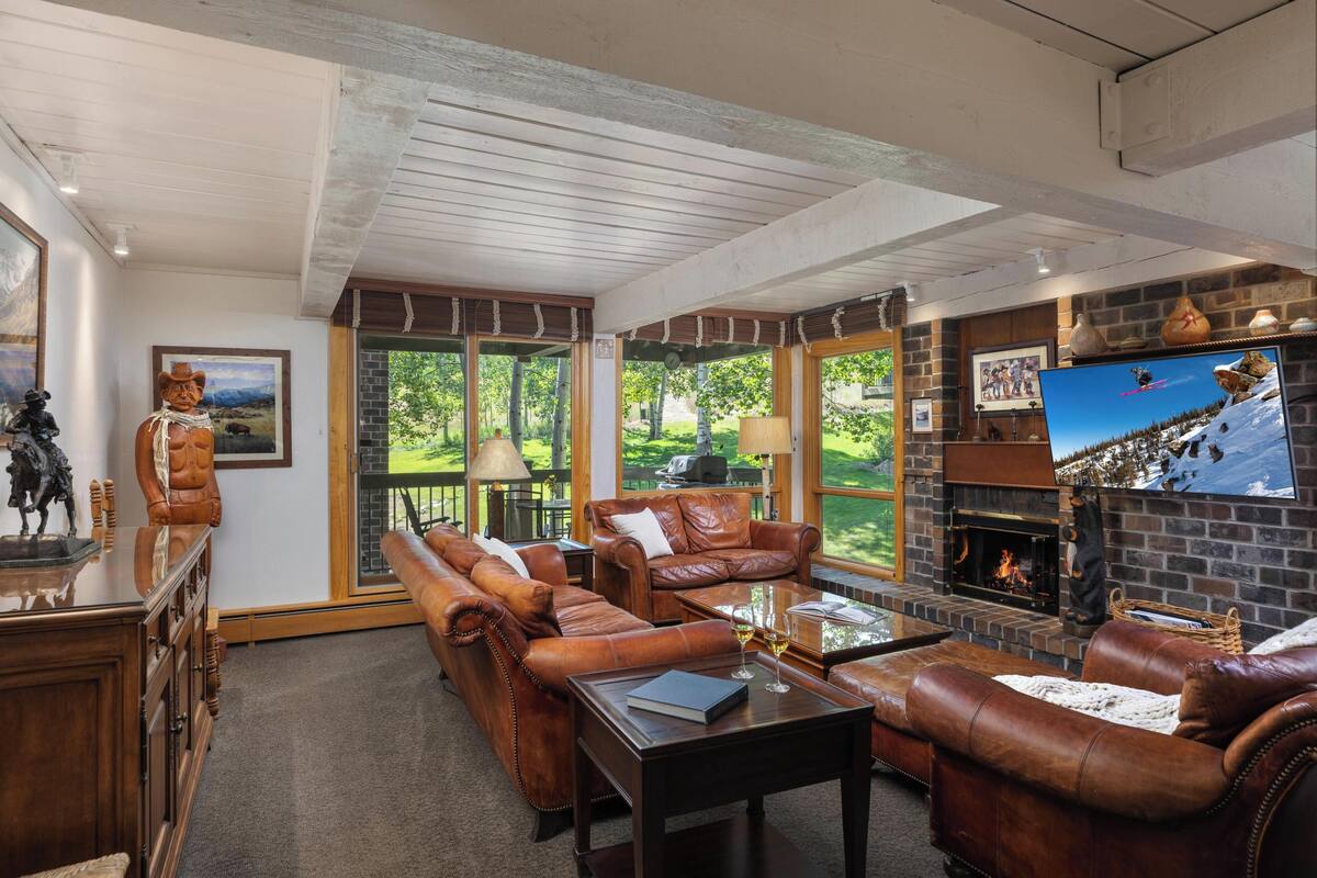 A cozy living room with leather sofas, a fireplace, and a large TV screen.