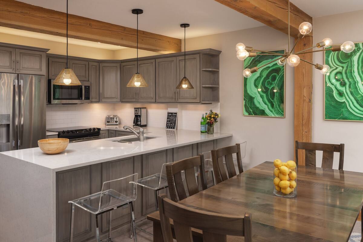 A modern kitchen with wooden beams, stainless steel appliances, and a central island with a bowl and lemons.