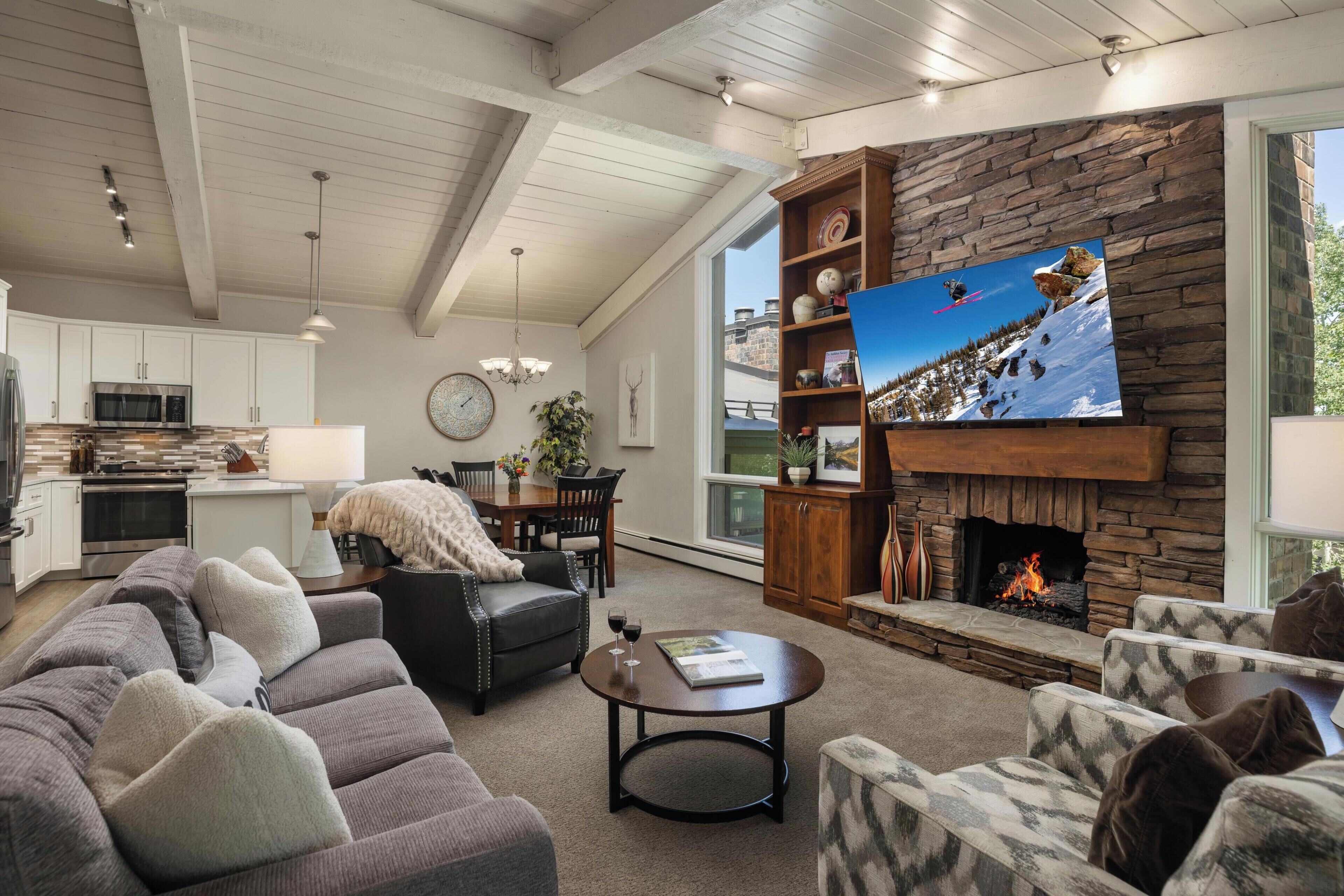 A modern living room with a fireplace, a television, and a dining area.