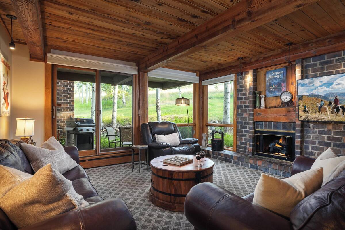 A cozy living room with leather sofas, a wooden coffee table, and a fireplace.