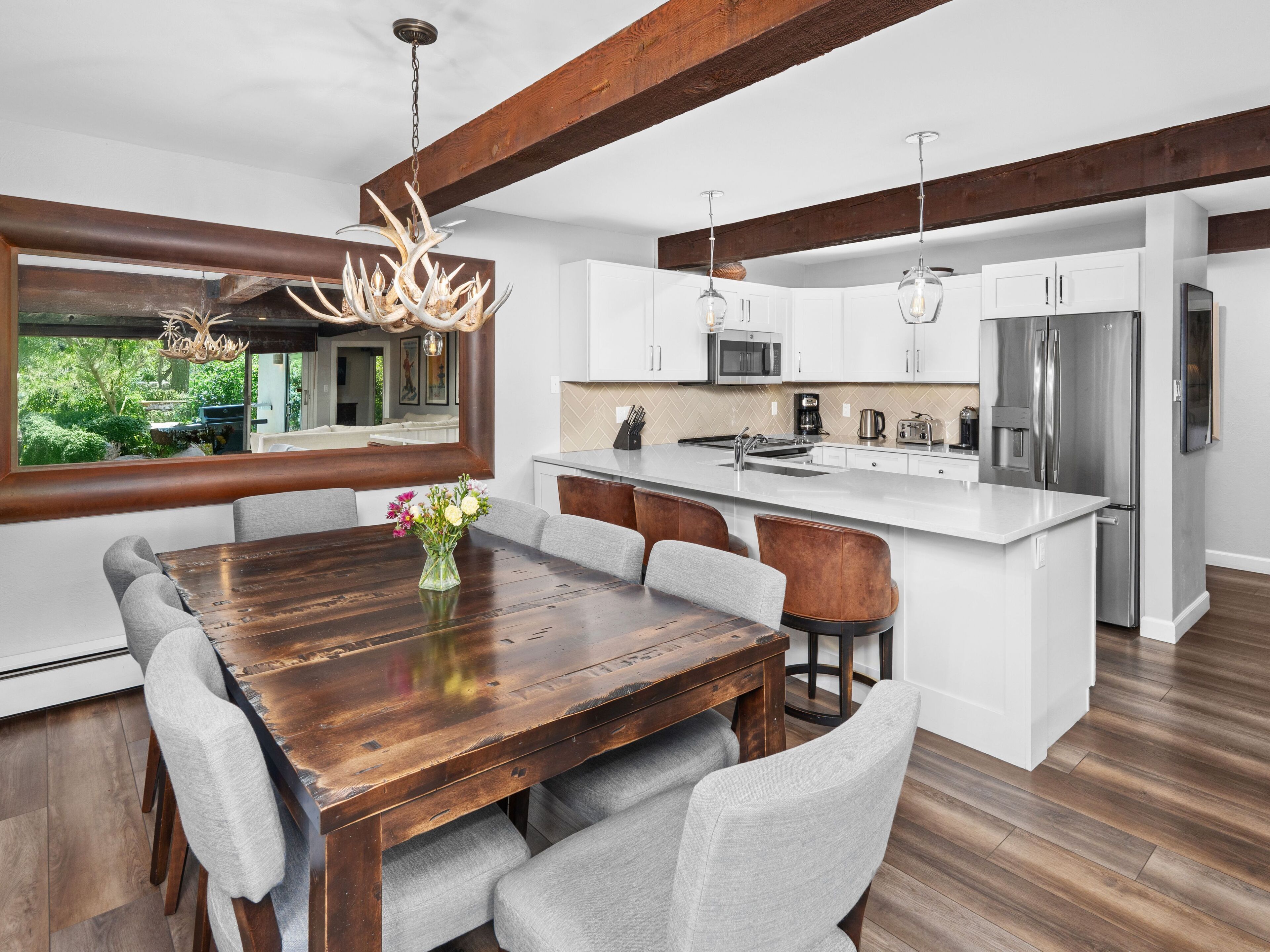 A modern kitchen with white cabinetry, a wooden dining table, and a large island.