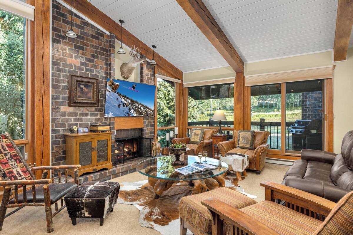 A cozy living room with a fireplace, leather furniture, and a glass coffee table.