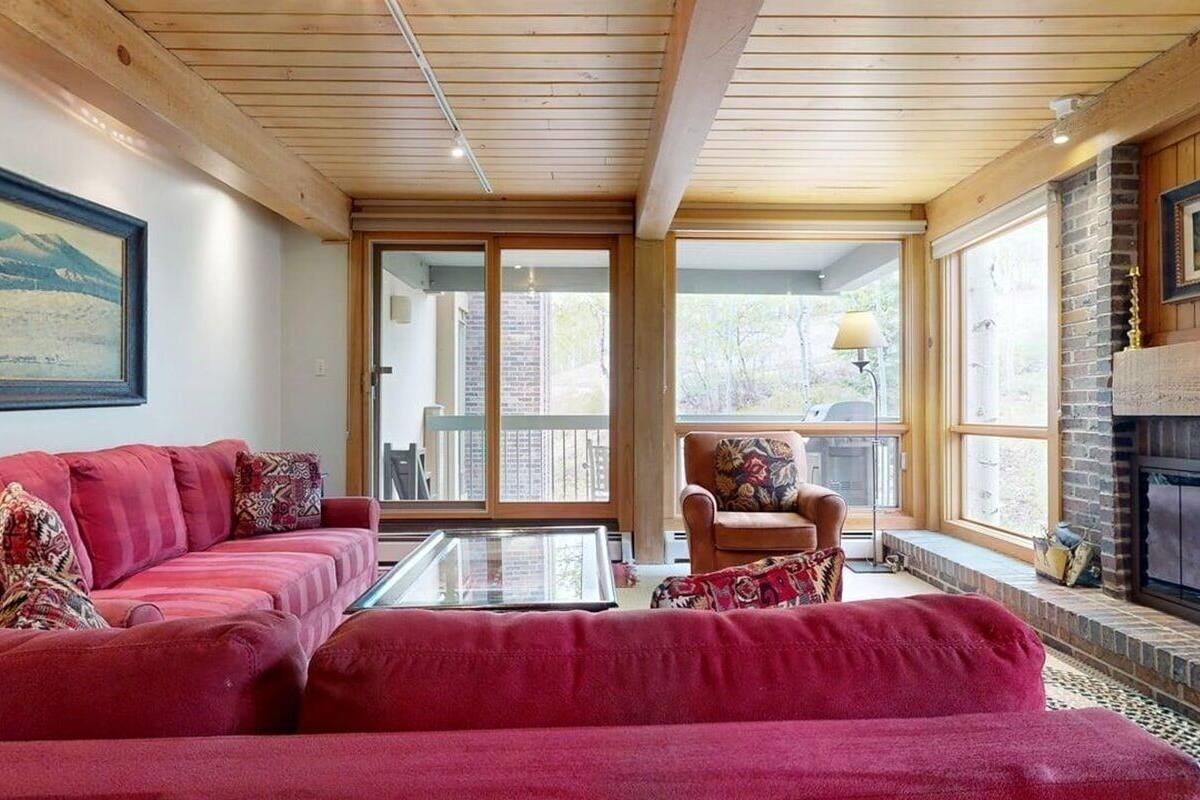 A living room with a red sofa, a glass coffee table, and a fireplace.