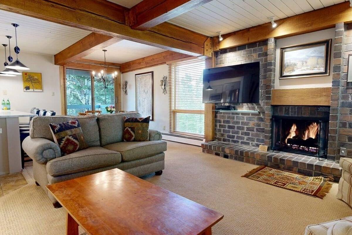 A cozy living room with a fireplace, a sofa, a coffee table, and a TV.