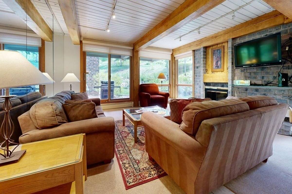 A cozy living room with a fireplace, comfortable seating, and large windows.