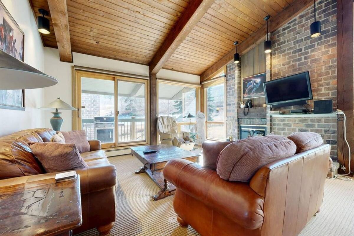 A cozy living room with leather sofas, a wooden coffee table, and a fireplace.