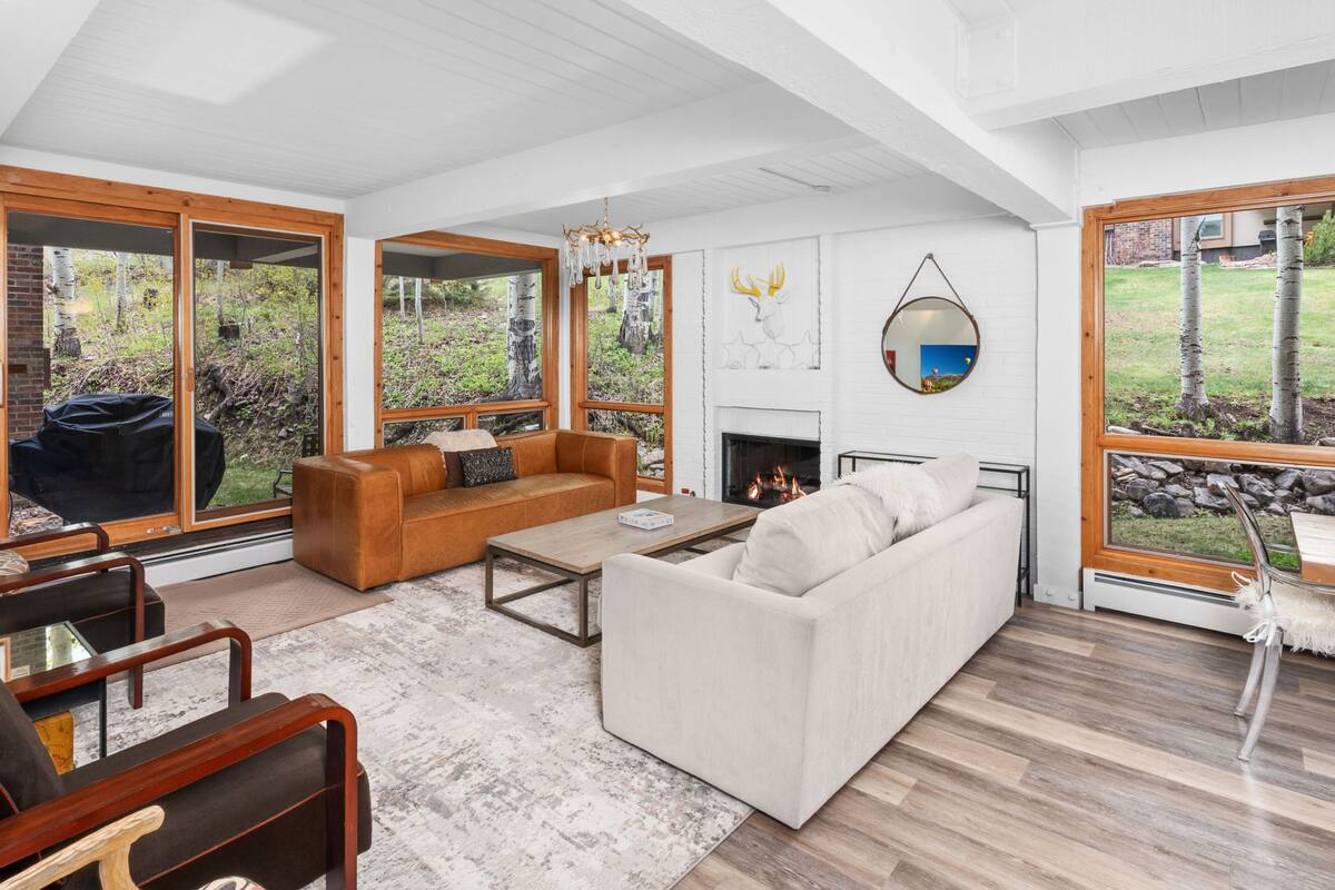 A spacious living room with a fireplace, large windows, and a view of the outdoors.