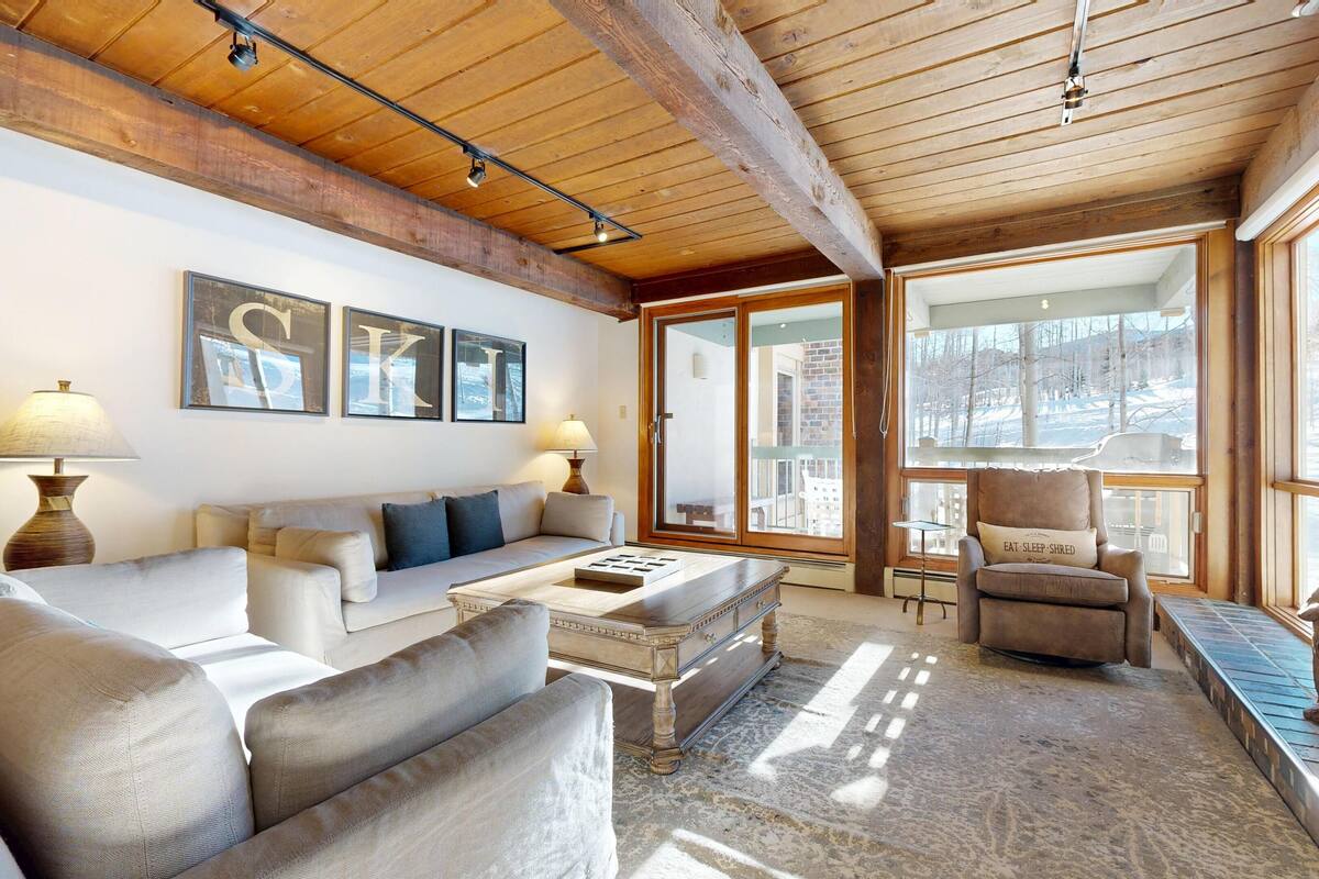 A cozy living room with a wooden ceiling, a sofa set, a coffee table, and a fireplace.