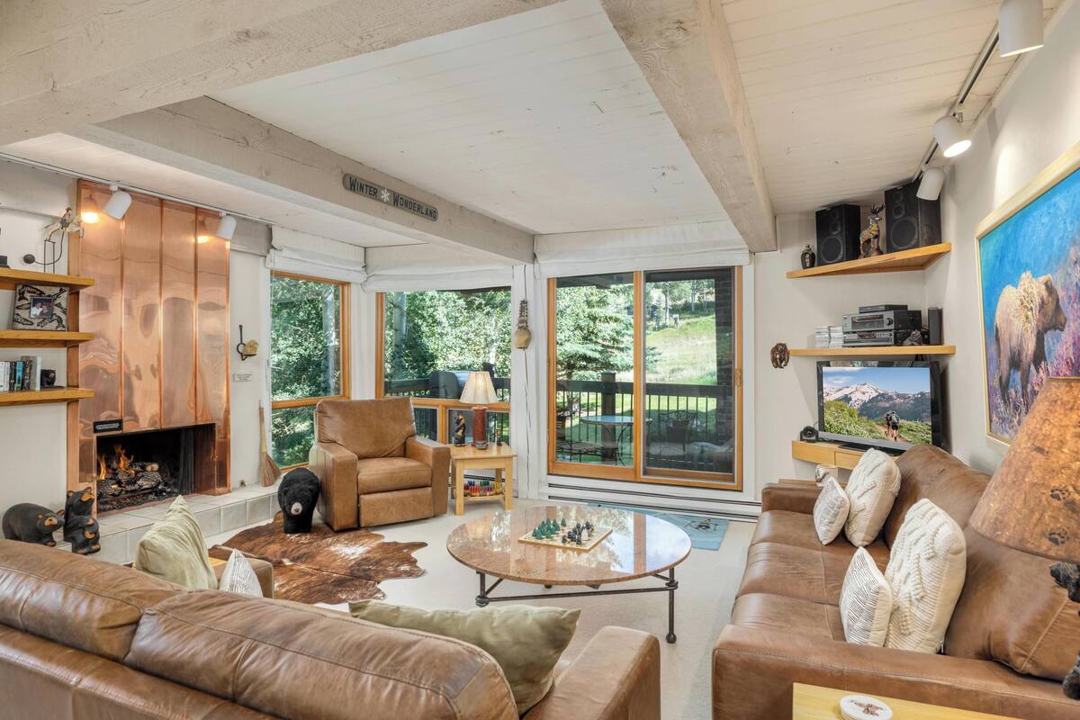 A cozy living room with a fireplace, leather sofas, a coffee table, and a television.