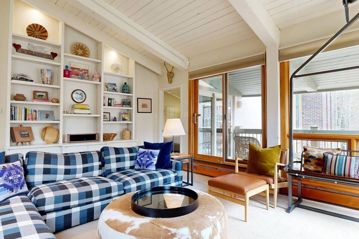 A living room with a checkered sofa, a round coffee table, and a bookshelf filled with various items.