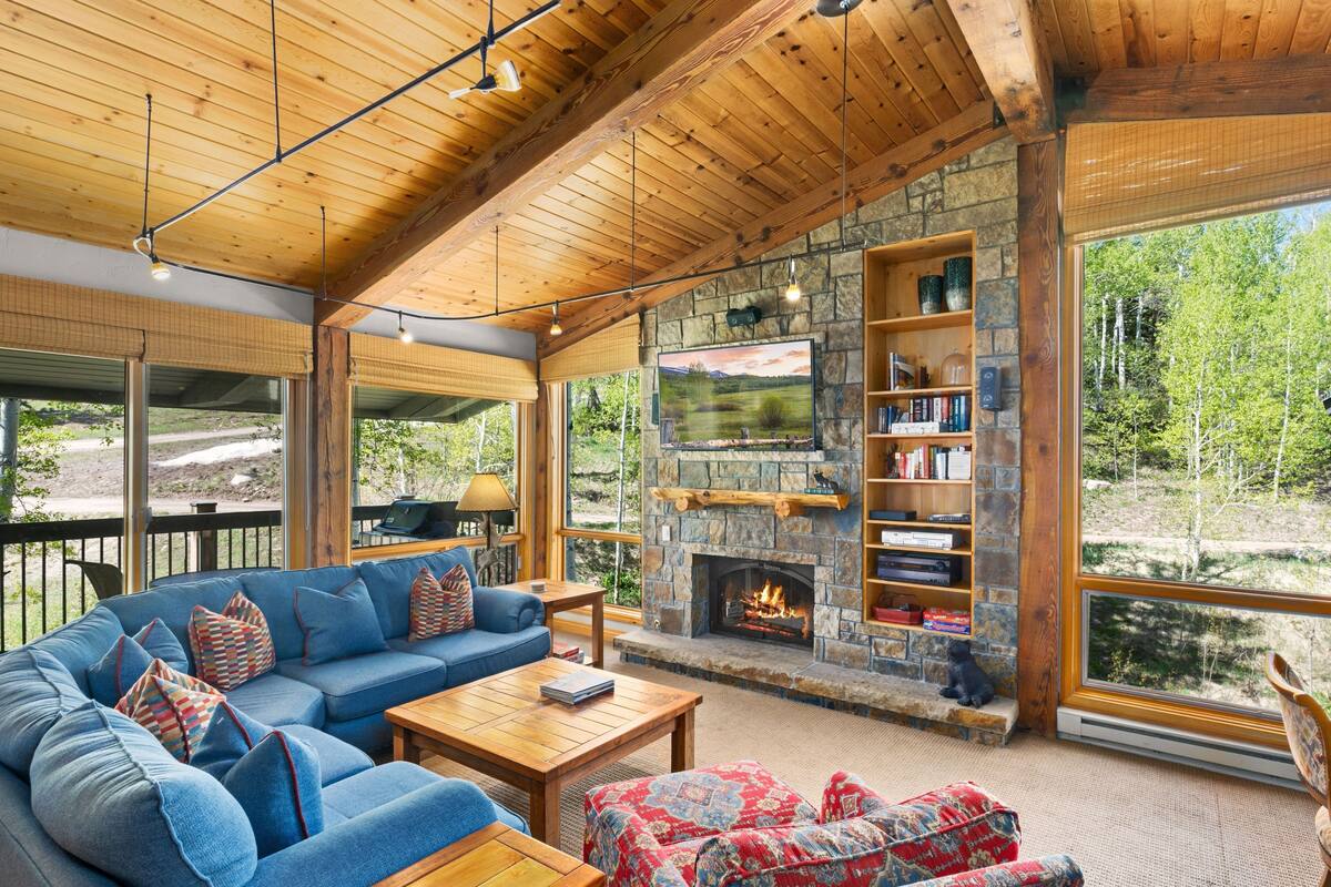 A cozy living room with a stone fireplace, a large sofa, and a television mounted above it.