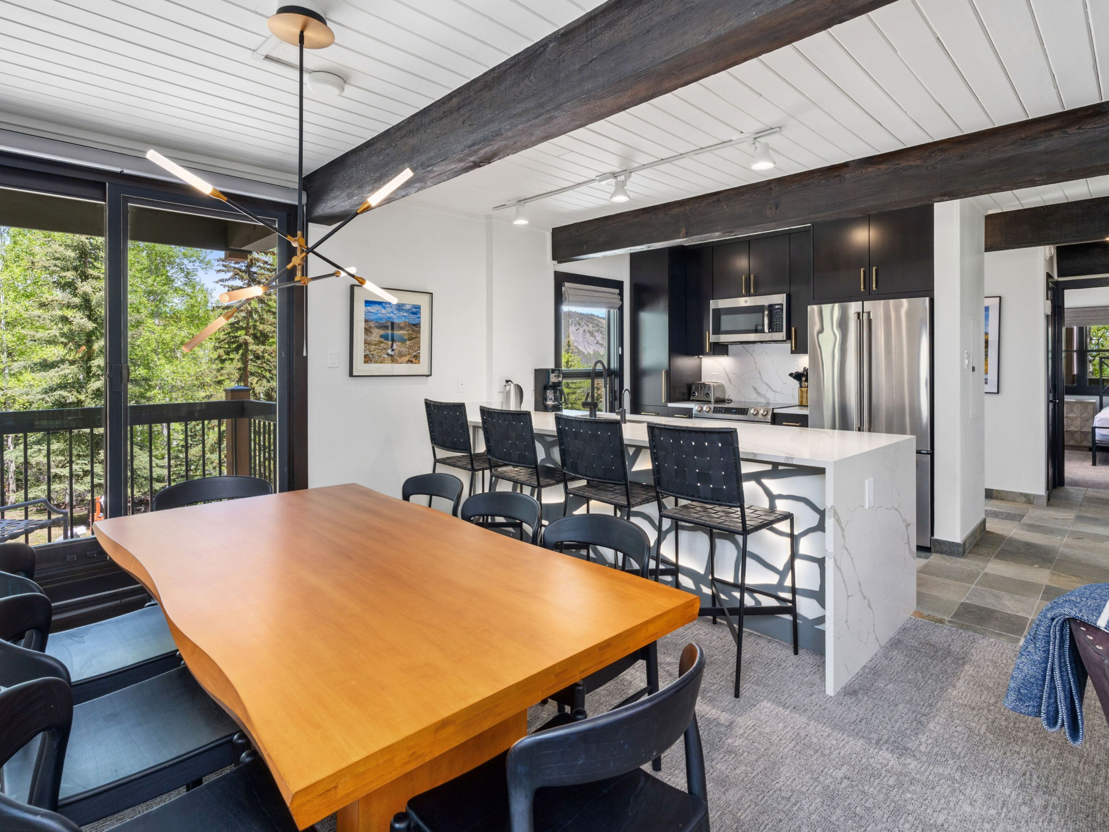 A modern kitchen with dark cabinetry, stainless steel appliances, and a large island.