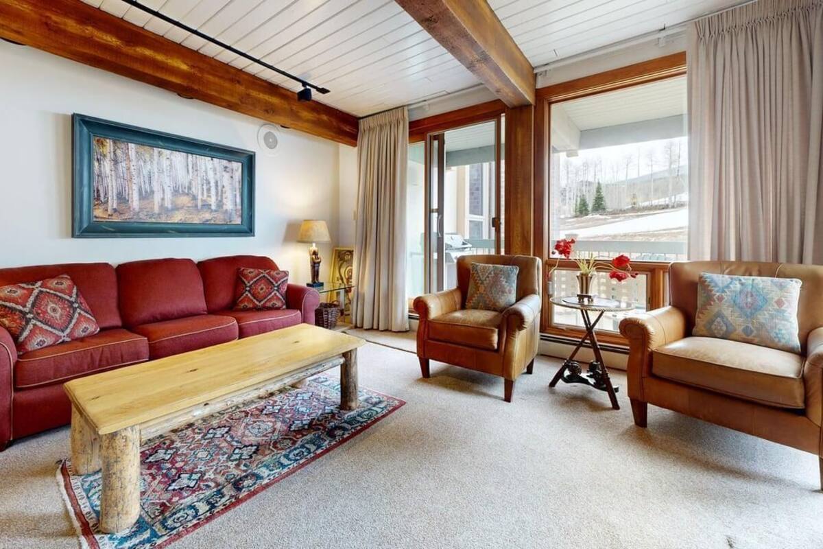 A cozy living room with a red sofa, a wooden coffee table, and two leather armchairs.
